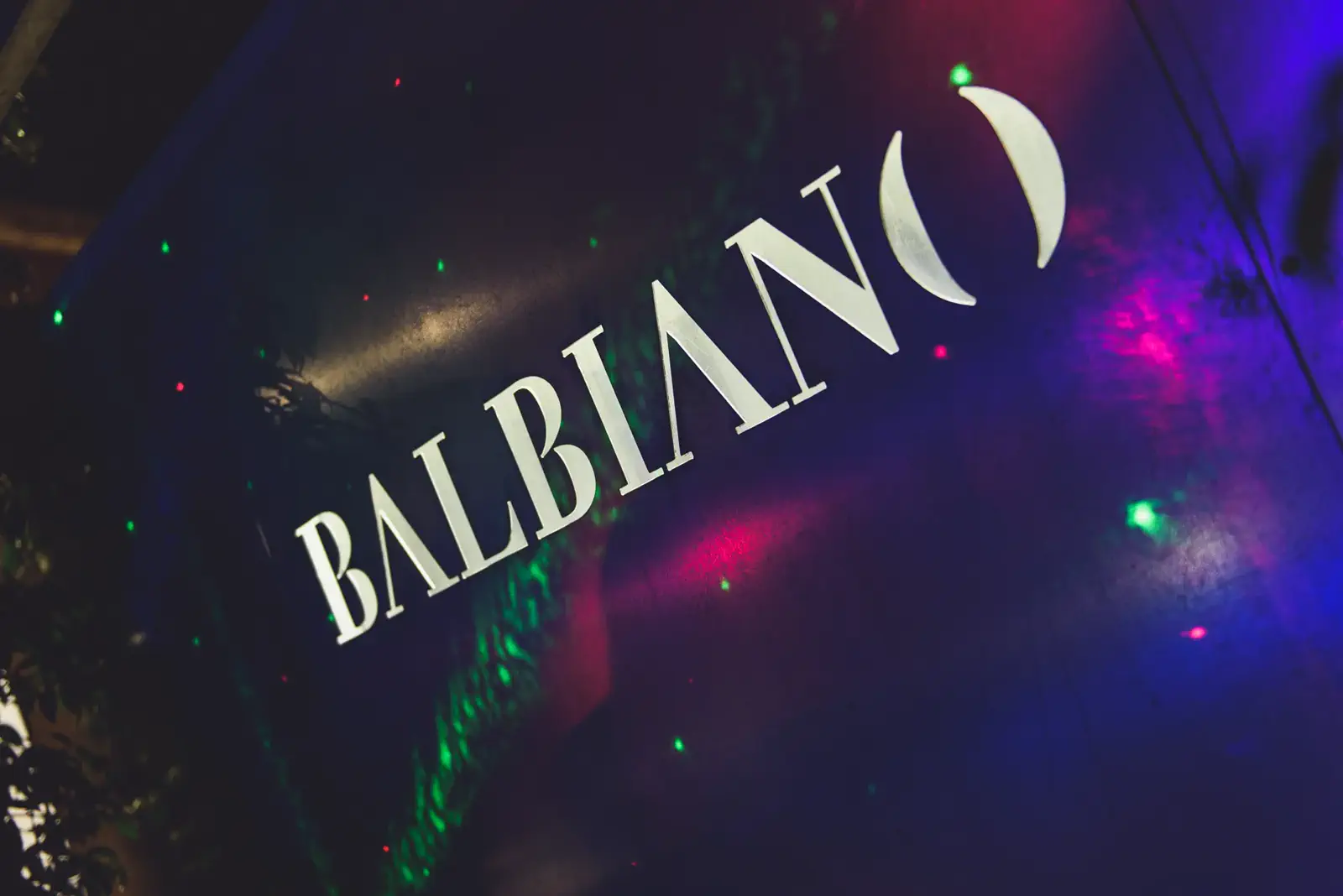 Insegna Balbiano illuminata dalle luci colorate durante una festa serale