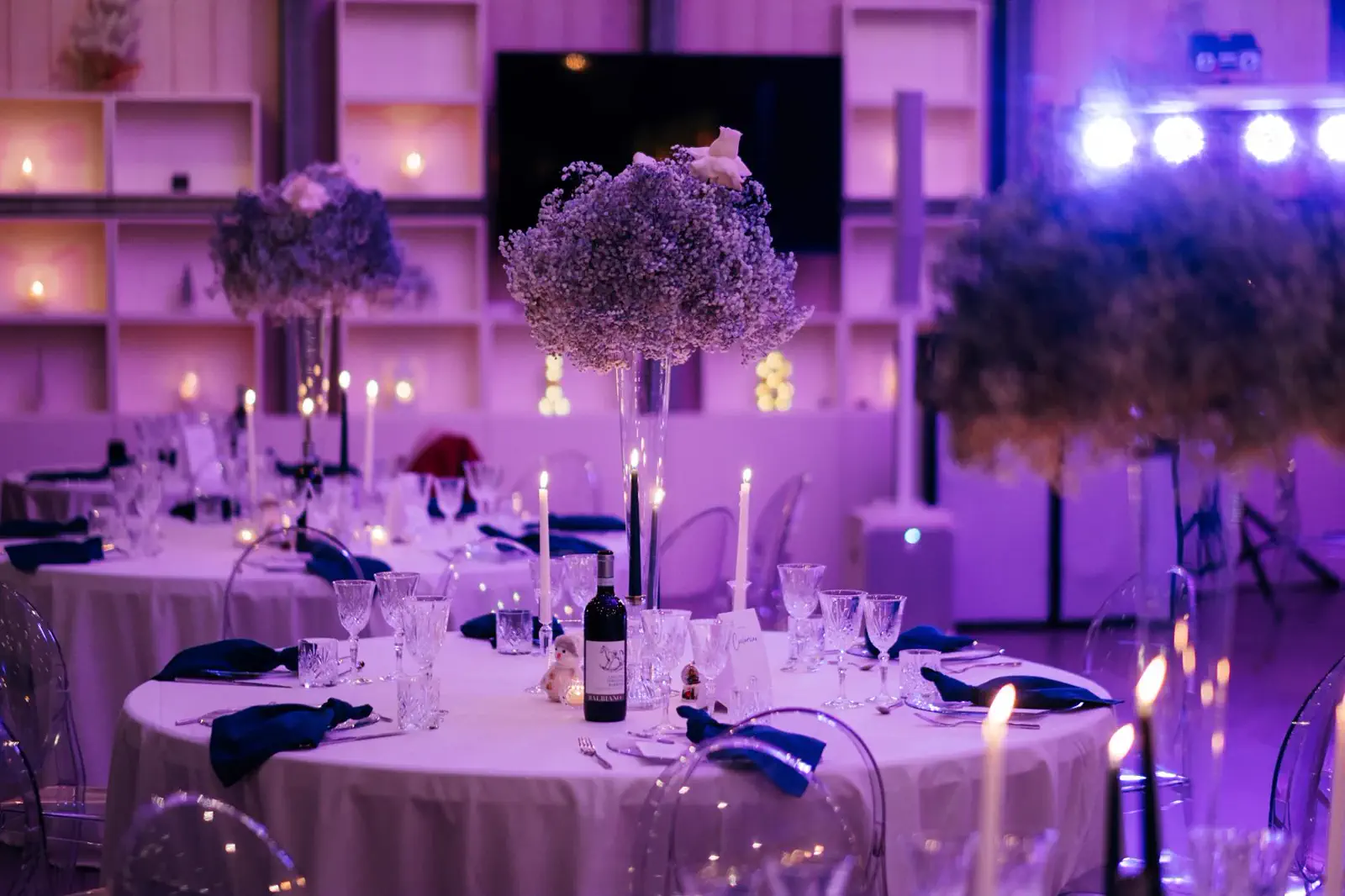 Sala vetrata allestita con tavoli e luci scenografiche per una festa di laurea