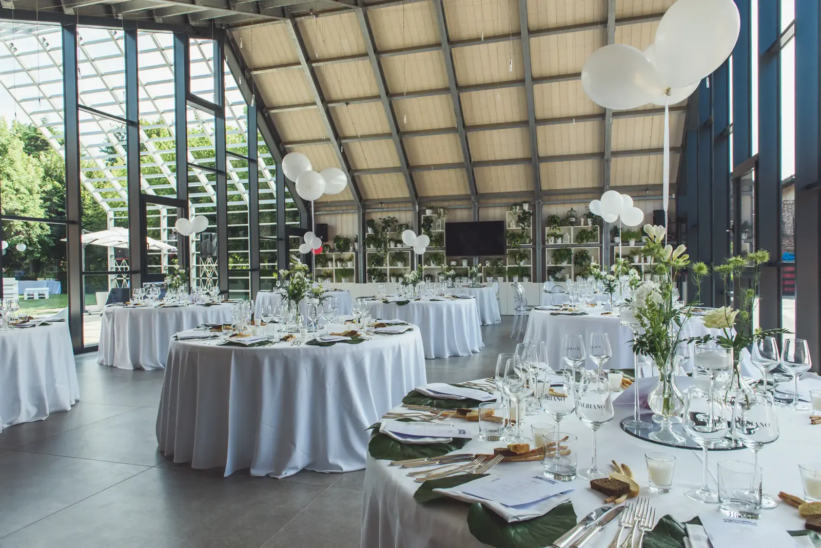 Sala vetrata allestita con tavoli rotondi e vista sul giardino